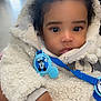 Blaze is registered to the contest to win money with this photo: baby, child, indoor, close_up, face, hand, clothing, jacket, pacifier, blue, cartoon, fur, warm, cute, person, young_child, portrait, expression, indoors, soft_lighting