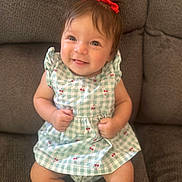 Katalia is registered to the contest to win money with this photo: baby, child, smiling, red_bow, dress, cherry_pattern, sitting, couch, indoor, cute, happy, infant, person, portrait, young_child, clothing, furniture, skin, head, face