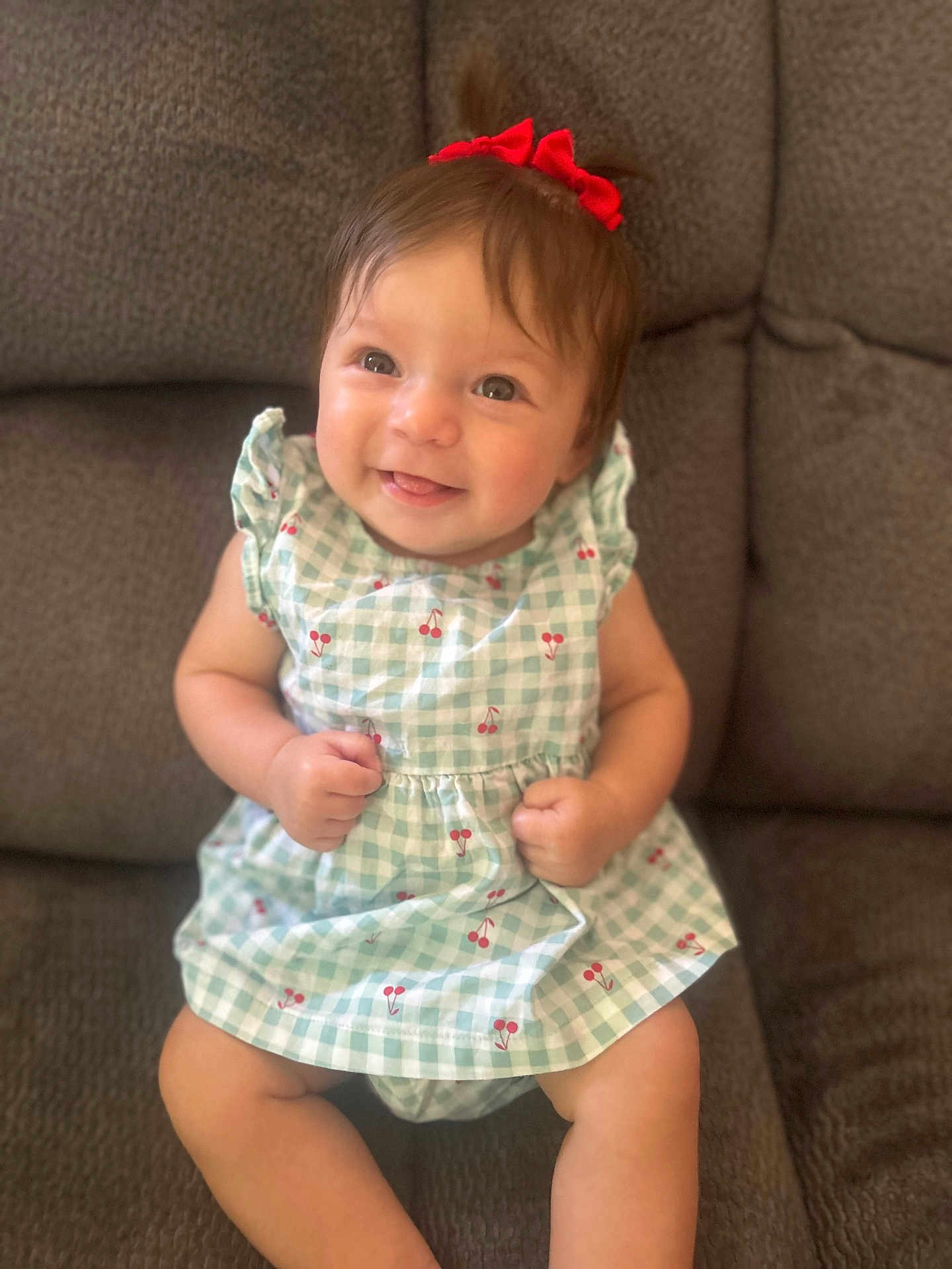 Katalia is registered to the contest to win money with this photo: baby, child, smiling, red_bow, dress, cherry_pattern, sitting, couch, indoor, cute, happy, infant, person, portrait, young_child, clothing, furniture, skin, head, face