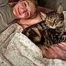 animal, bed, blanket, cat, comfort, cozy, cute, face, friendship, fur, human, indoor, person, pet, pink_bedspread, relaxation, resting, smiling, soft_texture, tabby_cat
