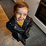 child, kid, leather_jacket, smiling, happy, indoors, kitchen, floor, tiles, appliance, cabinet, young, cute, portrait, fashion, playful, person, clothing, expression, standing