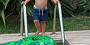 Hugo a rejoint le concours — aidez-le/la à gagner de superbes lots ! barefoot, boy, child, daytime, greenery, happy, inflatable_turtle, ladder, nature, outdoor, plants, playful, pool, shirtless, shorts, smiling, summer, swimming_pool, toy, water