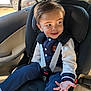 child, toddler, car_seat, seat_belt, car_interior, window, sunlight, smile, face, hand, clothing, jacket, pants, sock, hair, seat, safety, cute, portrait, indoor