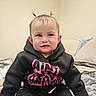 Ellamae joined the competition — help win amazing prizes! baby, child, hoodie, black_clothing, pink_text, pigtails, sitting, indoors, bed, blanket, pillow, cute, face, portrait, expression, young_child, cozy, clothing, person, casual