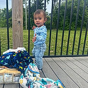 Koa joined the competition — help win amazing prizes! toddler, child, outdoor, deck, wood, blanket, bag, railing, greenery, trees, grass, clothing, jeans, shirt, footwear, expression, standing, person, daylight, nature