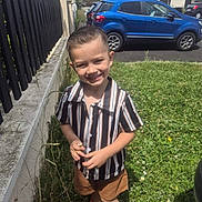Lorenzo participe au concours pour gagner de l'argent avec cette photo : child, boy, smiling, grass, flower, fence, car, shorts, shirt, outdoor, daylight, sidewalk, parked_car, happy, nature, building, sneakers, greenery, summer, portrait