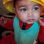 baby, child, hat, tonka, yellow_hat, bib, red_clothing, indoor, carpet, face, eyes, cute, infant, person, young_child, sitting, curious, closeup, headwear, portrait