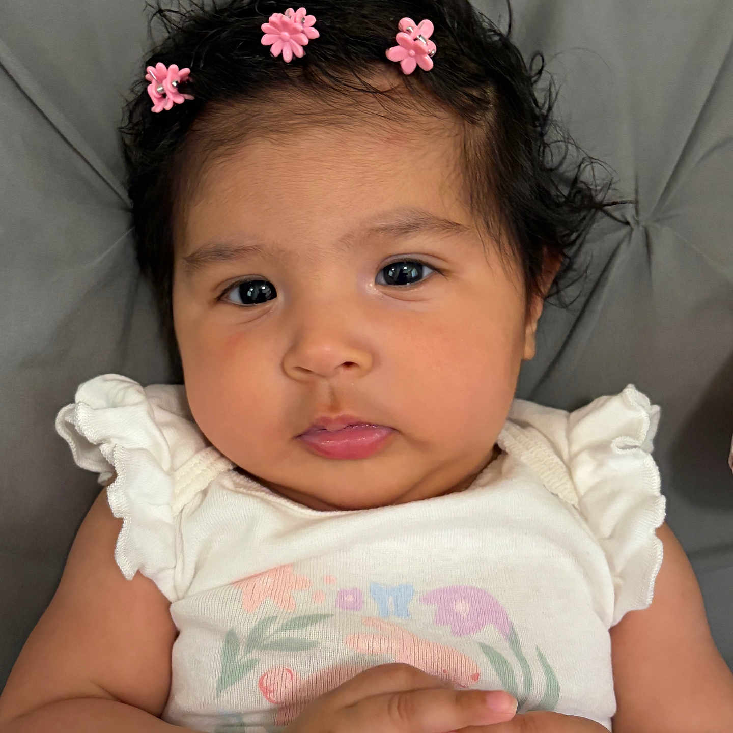 Athalea joined the competition — help win amazing prizes! baby, infant, child, face, hairclip, pink_flower, white_clothing, hands, expression, portrait, closeup, cute, soft_texture, indoor, skin, person, photography, young, adorable, resting