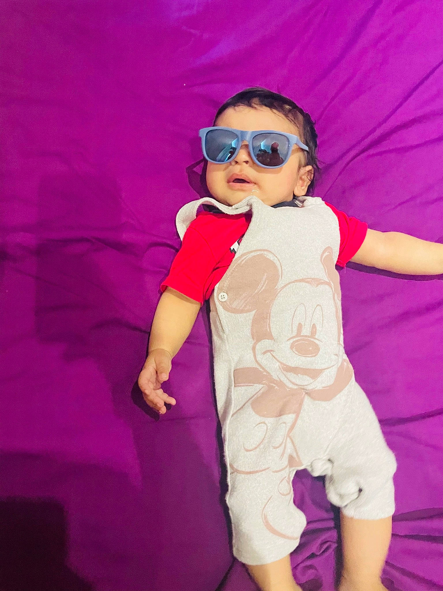 Avi is registered to the contest to win money with this photo: arm, baby_toddler_clothing, cool, eyewear, facial_expression, finger, goggles, hand, happy, human_body, outerwear, person, pink, purple, sleeve, sunglasses, textile, thigh, toddler, violet