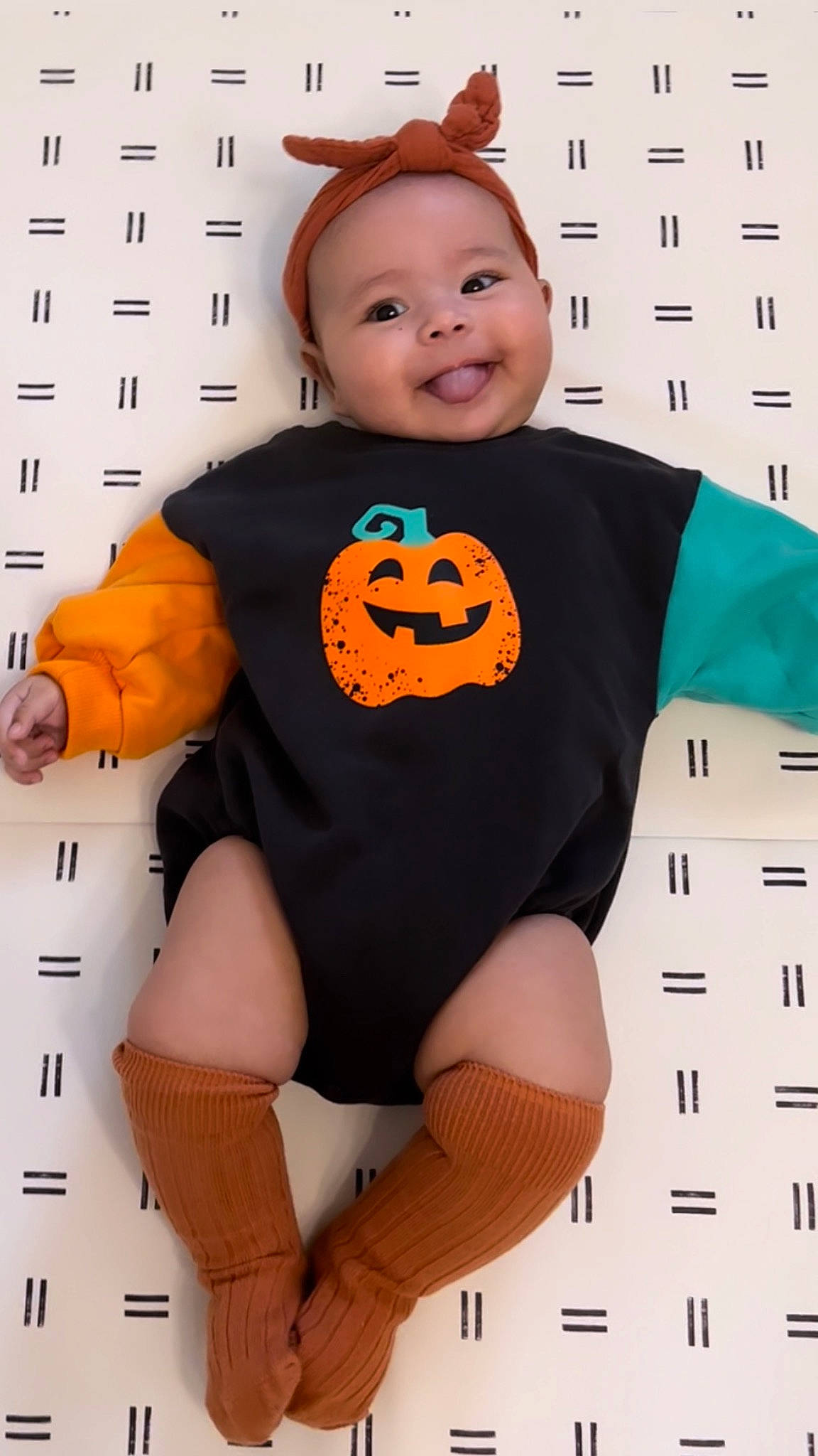 Maya is registered to the contest to win money with this photo: arm, baby_toddler_clothing, calabaza, clothing, finger, hair, hairstyle, happy, headwear, human_body, joint, joy, knee, leg, neck, orange, outerwear, person, pumpkin, sleeve