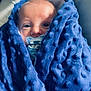 baby, blanket, blue, pacifier, cushion, face, foot, sock, infant, soft_texture, cozy, resting, child, indoors, comfort, wrapped, cute, closeup, person, portrait