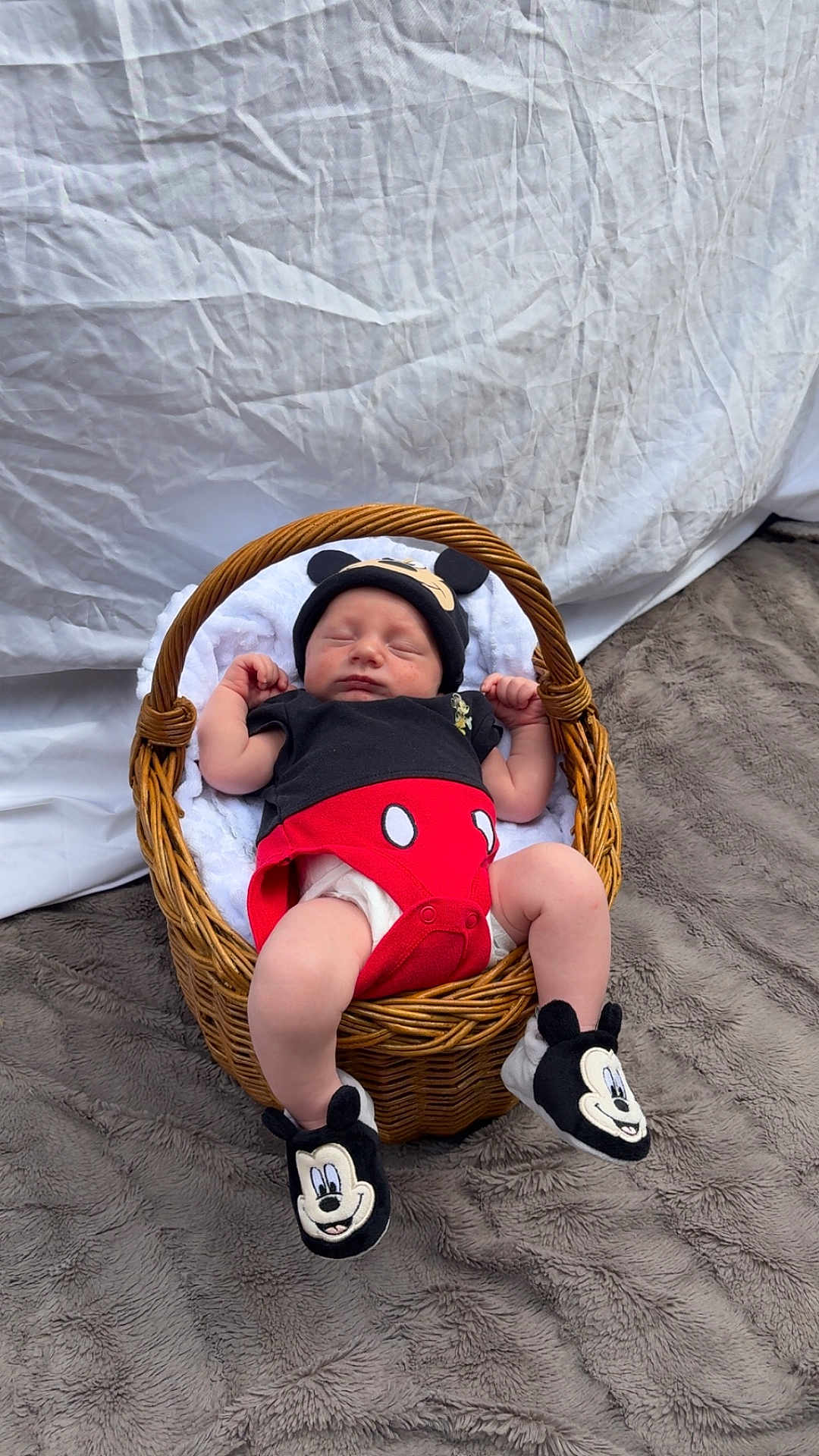 Eden participe au concours pour gagner de l'argent avec cette photo : baby, newborn, sleeping, basket, mickey_mouse, hat, booties, blanket, wicker, clothing, diaper, indoor, soft_texture, fur_rug, white_background, cute, infant, child, person, resting