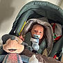 baby, pacifier, stroller, plush_toy, mickey_mouse, blanket, indoor, child, cute, infant, soft_toy, face, head, person, clothing, comfort, seated, young_child, toy, rest