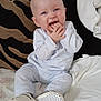 Oliver is registered to the contest to win money with this photo: baby, child, pajamas, bed, blanket, pillow, footwear, hand, face, smile, indoor, cute, infant, blue_clothing, sitting, young, person, happy, cozy, home