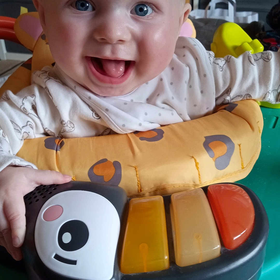 Oliver joined the competition — help win amazing prizes! baby, blue_eyes, child, clothing, colorful, expression, face, fun, hand, happy, indoor, infant, joyful, piano, plastic, play_area, playtime, seat, smiling, toy