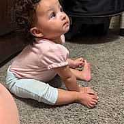 Rosaleigh joined the competition — help win amazing prizes! toddler, child, curly_hair, carpet, pink_shirt, white_pants, barefoot, indoor, baby_carrier, brown_sofa, carpet_floor, looking_up, sitting, young_child, home_interior, hands_on_floor, cute, floor, person, curious