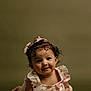 baby, child, smiling, tummy_pose, curly_hair, pink_bows, dress, floral_pattern, ribbon, cute, portrait, studio, innocent, adorable, infant, girl, young_child, soft_lighting, background, happy