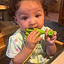Rosaleigh joined the competition — help win amazing prizes! toddler, child, curly_hair, toy, giraffe_toy, high_chair, pastel_clothing, floral_pattern, indoor, restaurant, wooden_furniture, table, cute, baby, chewing, curious, seated, brown_eyes, casual, warm_lighting