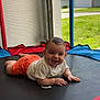 baby, backyard, child, colorful_padding, crawling, daylight, face, grass, happy, home, mesh_screen, orange_shorts, outdoor, person, playtime, smiling, sunny, toddler, trampoline, white_shirt