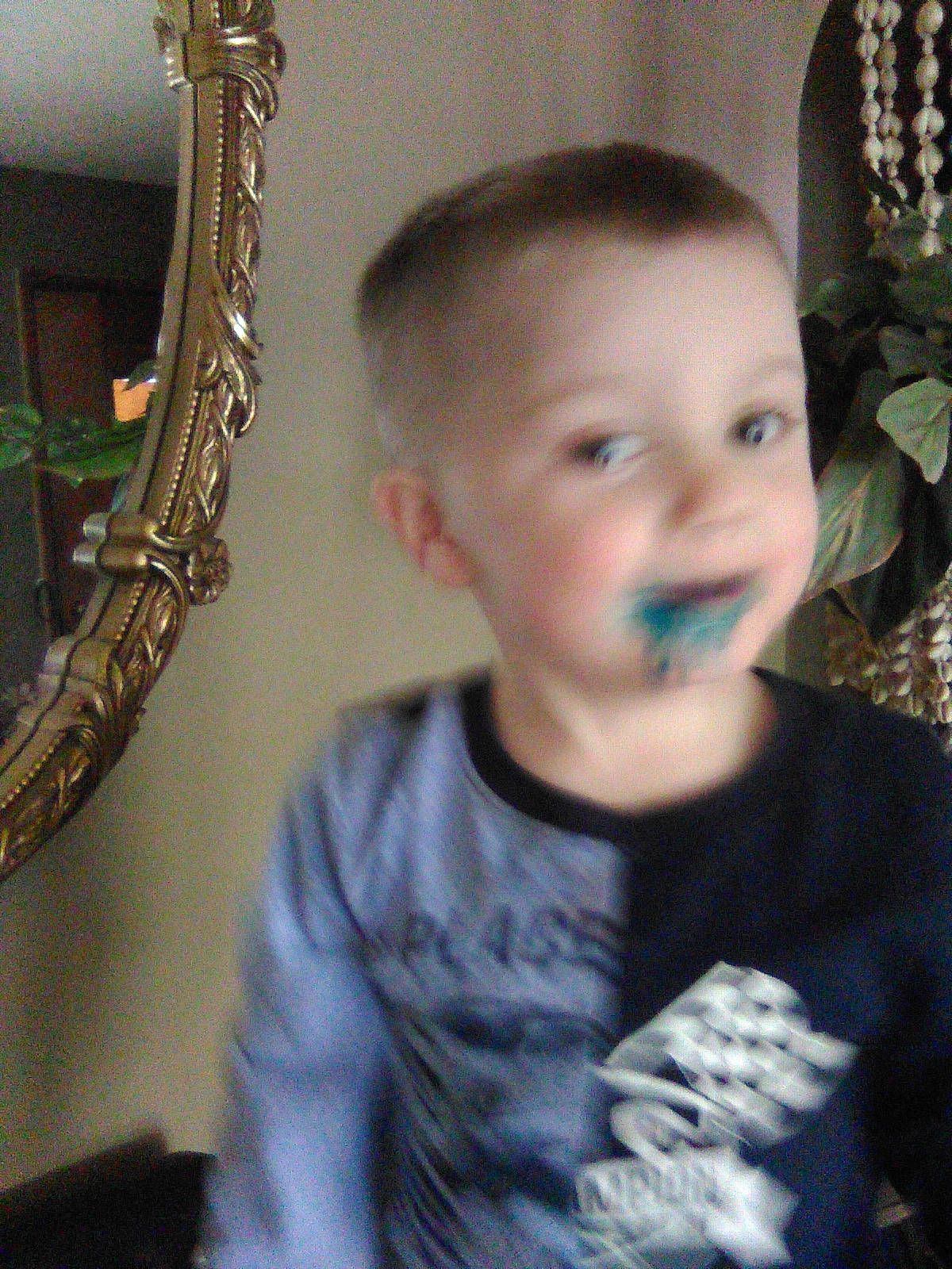 William is registered to the contest to win money with this photo: baby, baby_toddler_clothing, cheek, child, ear, flowerpot, fun, happy, head, houseplant, mammal, nose, organ, person, plant, room, standing, t_shirt, toddler, vertebrate