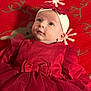 baby, infant, red_dress, headband, bow, blanket, snowflake_pattern, holiday_theme, reindeer_pattern, cute, child, portrait, face, lying_down, indoors, soft_lighting, festive, tulle, clothing, adorable