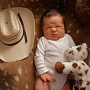 Rowen is registered to the contest to win money with this photo: newborn, baby, infant, child, portrait, sleeping, scrunched_face, white_onesie, plush_toy, giraffe, cowboy_hat, animal_print, blanket, cozy, indoors, lying_down, close_up, face, photography, cute