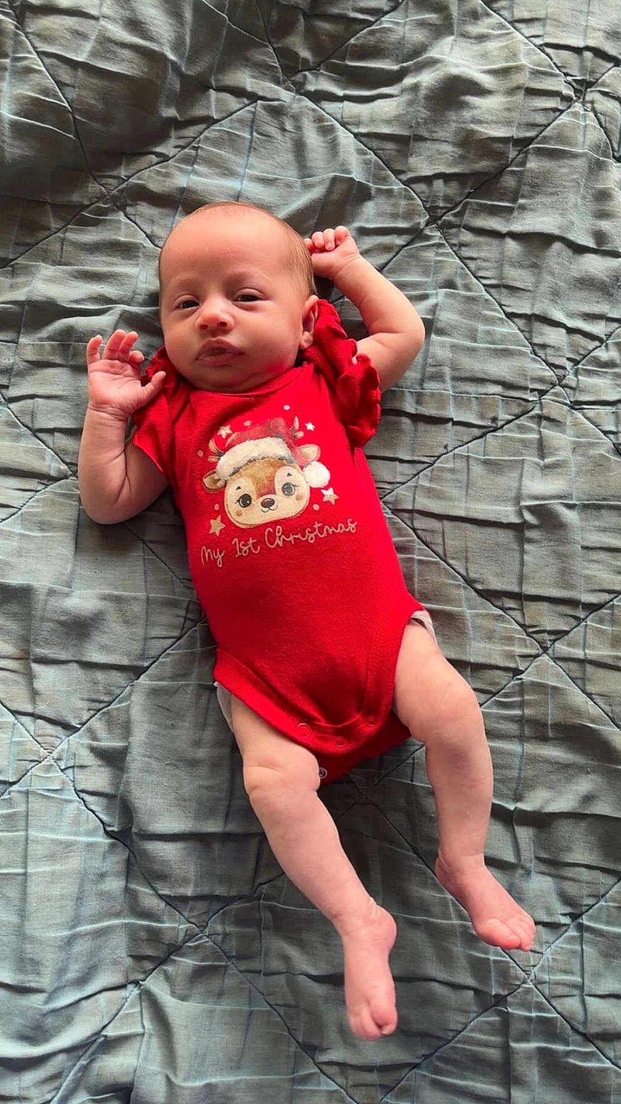 Sienna joined the competition — help win amazing prizes! baby, infant, red_onesie, christmas_clothing, lying_down, quilt, blanket, cute, newborn, holiday_theme, face, arms, legs, skin, indoors, resting, expression, small_hands, small_feet, child