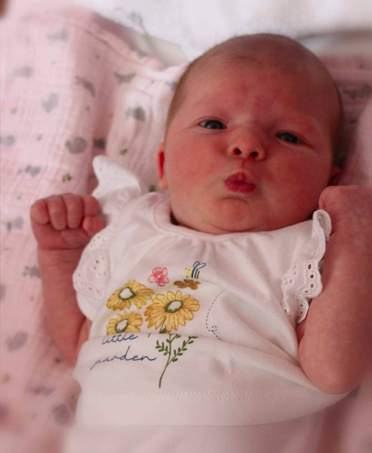 Kacie is registered to the contest to win money with this photo: baby, bedding, cheek, child, eye, face, finger, hand, head, iris, linens, lip, mouth, nose, person, pink, skin, textile, thumb, toddler