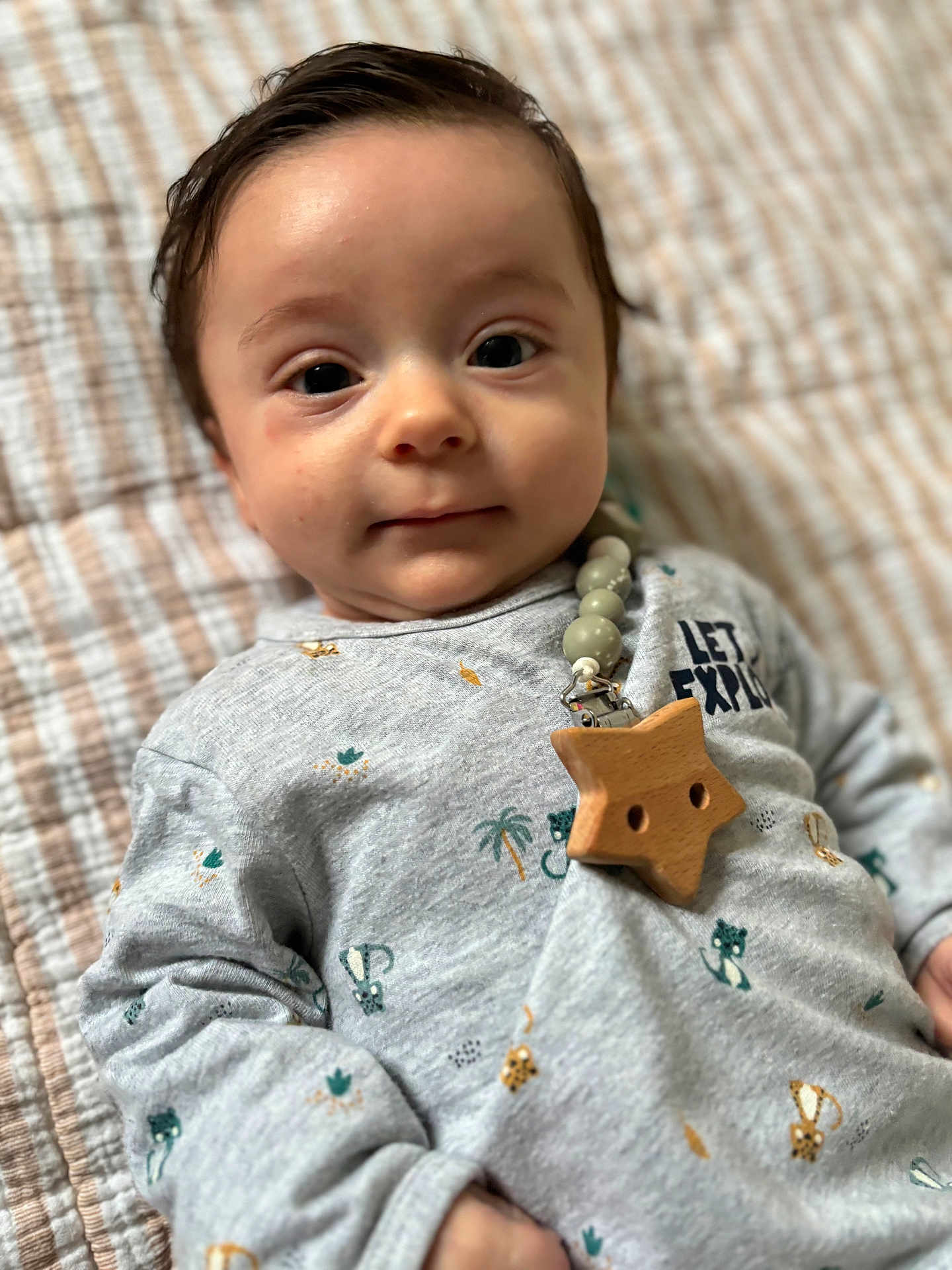 Julian a rejoint le concours — aidez-le/la à gagner de superbes lots ! baby, infant, portrait, face, eyes, onesie, blanket, wooden_star, beaded_clip, star_clip, close_up, indoor, soft_lighting, lying_down, hair, skin, animal_print, cozy, curious_expression, bokeh_background