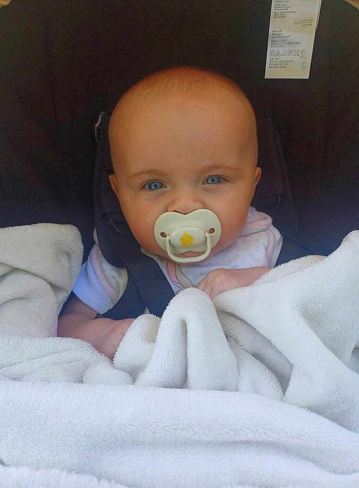 Kelsey is registered to the contest to win money with this photo: baby, pacifier, blanket, car_seat, child, infant, blue_eyes, face, head, clothing, person, sitting, closeup, cute, indoors, young_child, comfort, soft, wrapped, seatbelt
