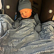 Liam is registered to the contest to win money with this photo: newborn, baby, sleeping, car_seat, blanket, hat, infant, child, cozy, personalized_blanket, blue, clothing, cute, resting, indoors, face, portrait, small, bundle, peaceful