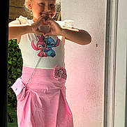 Léana a rejoint le concours — aidez-le/la à gagner de superbes lots ! Stitch, cartoon_character, casual, child, crossbody_purse, doorway, fashion, girl, greenery, hand_gesture, happy, heart_shape, outdoor, pink_skirt, playful, portrait, smile, sunlight, wall, white_top