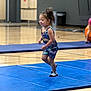 Kairi is registered to the contest to win money with this photo: child, toddler, gymnasium, blue_mat, running, dinosaur_outfit, smiling, indoors, wooden_floor, socks, playful, young_child, active, sport, exercise, person, fun, hair_tied, gymnastics, happy