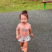 Kairi joined the competition — help win amazing prizes! toddler, child, playground, grass, bench, tree, sandals, shorts, shirt, car_graphic, text_on_shirt, walking, outdoor, park, face, person, summer_clothing, cute, confident, messy_face