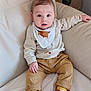 baby, child, infant, couch, leather, clothing, socks, shoes, bib, fox, pants, sitting, furniture, indoor, table, decor, curious, face, person, expression