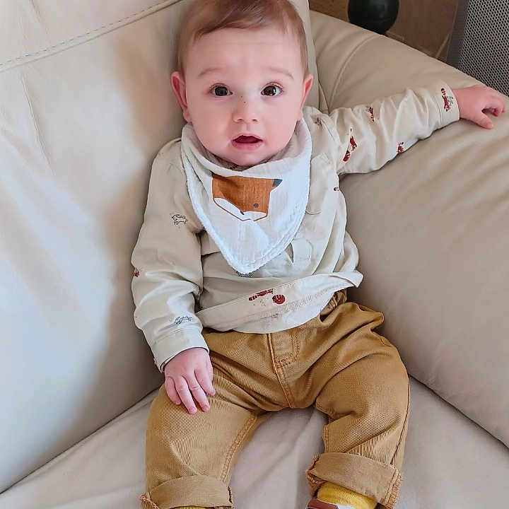Gabriel a rejoint le concours — aidez-le/la à gagner de superbes lots ! baby, bib, child, clothing, couch, curious, decor, expression, face, fox, furniture, indoor, infant, leather, pants, person, shoes, sitting, socks, table