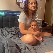 Kristiahnna joined the competition — help win amazing prizes! child, baby, bed, blanket, curly_hair, indoor, person, smiling, sitting, young_girl, furniture, mirror, wall_art, water_bottle, shorts, tshirt, skin, hand, foot, room