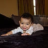 Isaac is registered to the contest to win money with this photo: baby, child, infant, smiling, happy, portrait, lying_down, tummy_time, bed, blanket, bedroom, indoor, face, eyes, curly_hair, white_clothing, reaching, crawling, cozy, photography