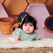 Violette is registered to the contest to win money with this photo: baby, infant, child, face, curious, hair_bow, fluffy_rug, soft_lighting, indoor, decor, balloons, portrait, cute, crawling, green_dress, young_child, closeup, expression, floor, background