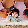 baby, infant, child, face, curious, hair_bow, fluffy_rug, soft_lighting, indoor, decor, balloons, portrait, cute, crawling, green_dress, young_child, closeup, expression, floor, background