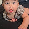 baby, child, infant, portrait, face, eyes, wide_eyes, open_mouth, surprised, smiling, lying_down, bed, bedroom, indoor, striped_clothing, brown_hair, hand, adult_hand, parent, close_up