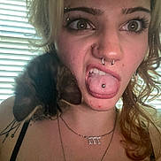 Momo is registered to the contest to win money with this photo: woman, face, tongue, piercing, kitten, cat, shoulder, hair, indoor, window, blinds, tattoo, necklace, expression, cute, pet, animal, light, portrait, funny_face