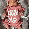 baby, infant, pink_outfit, headband, bow, baby_seat, cushion, cute, child, newborn, clothing, portrait, indoors, person, soft_texture, lying_down, looking, small_hands, footwear_none, baby_toy