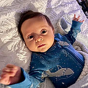 Davi is registered to the contest to win money with this photo: baby, infant, onesie, blue_clothing, shark_design, blanket, white_blanket, gray_blanket, face, hands, lying_down, bed, cute, portrait, indoor, soft_lighting, child, newborn, person, cozy