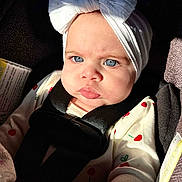 Sophia joined the competition — help win amazing prizes! baby, child, blue_eyes, white_headband, bow, car_seat, seatbelt, cherry_pattern, sunlight, infant, clothing, face, portrait, expression, young_child, cute, indoors, sitting, serious, closeup