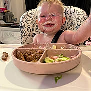 Harper-Kay joined the competition — help win amazing prizes! baby, background, black_curtain, cheeks, child, clothing, food, high_chair, indoor, kitchen, meat, messy_face, nose, person, plate, reaching, salad, seat, smiling, table