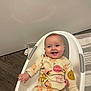 baby, child, smiling, onesie, pumpkin_pattern, white_baby_seat, floor, wooden_floor, rug, hand, happy, infant, cute, indoors, portrait, sitting, clothing, face, head, person