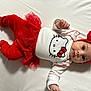 baby, infant, hello_kitty, red_clothing, white_background, headband, bow, cute, lying_down, child, portrait, toddler, one_person, indoors, soft_texture, smiling, small_hands, closeup, festive, glitter