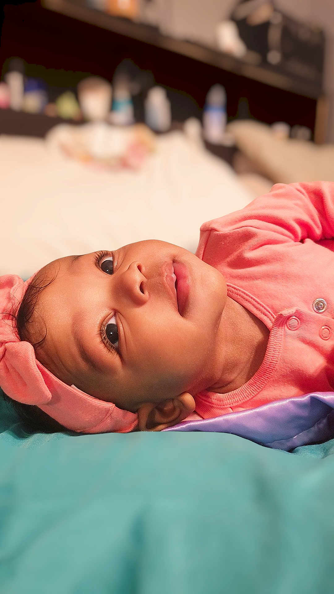 Isabella is registered to the contest to win money with this photo: baby, infant, headband, pink_clothing, bed, blanket, closeup, face, portrait, lying_down, child, cute, soft_light, indoors, young_child, sleepwear, expression, skin, eyelashes, head