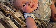 Rex joined the competition — help win amazing prizes! baby, child, smiling, couch, patterned_fabric, indoor, portrait, cute, arm, blond_hair, striped_shirt, bib, relaxed, infant, closeup, soft_light, happy, person, home, cozy